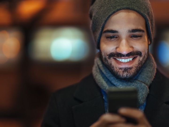 A young man smiling into his phone